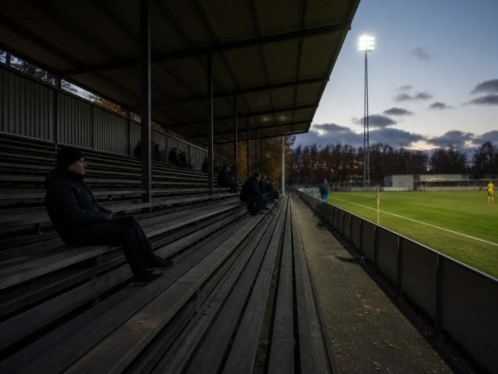 Nästan tom läktare på en mindre svensk fotbollsarena i skymningen